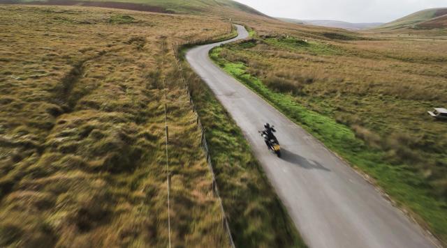   Un motociclista solitario che percorre una strada di montagna del Galles